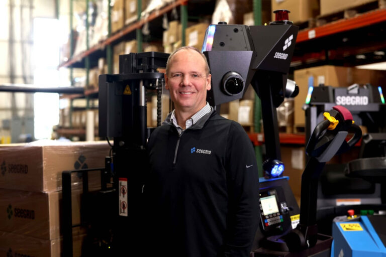 Joe Pajer, CEO and President of Seegrid in industrial facility with Lift RS1 AMR and Tow Tractor S7 AMR image