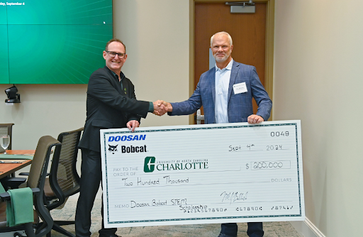 Doosan Bobcat North America President Mike Ballweber (R) shakes hands with Dr. Robert Keynton, Dean of William States Lee College of Engineering at UNC Charlotte (L), as they donate $200,000 to support student scholarships. image
